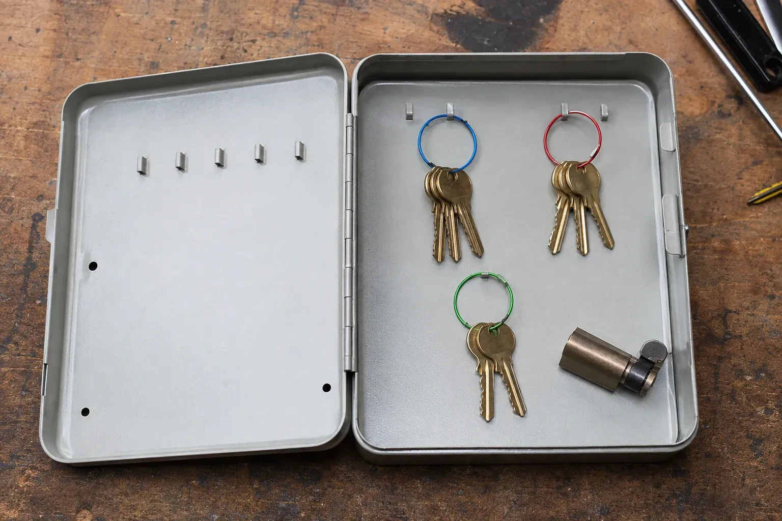 Three groups of keys on colored rings in an open metal key cabinet. — Master Key System Design, Toronto